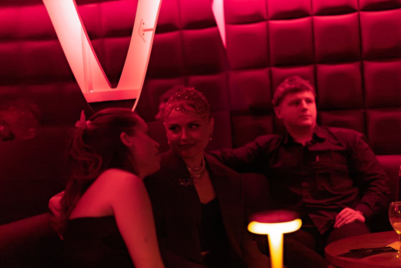 Guests sharing a moment in a red-lit booth at Stable 54.