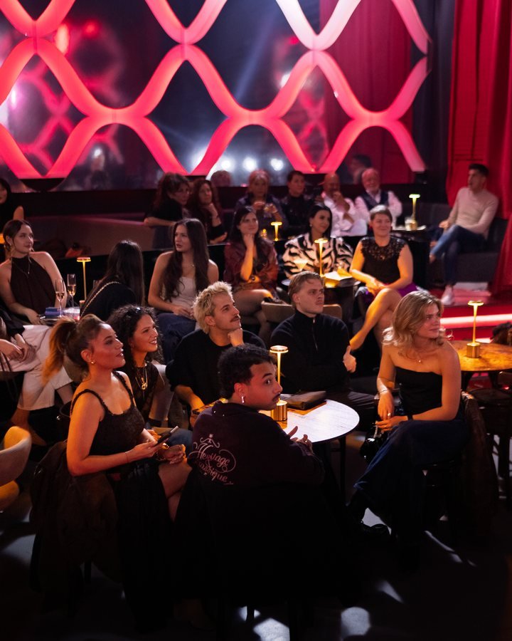 A full room of guests watching the show beneath the red lattice wall.
