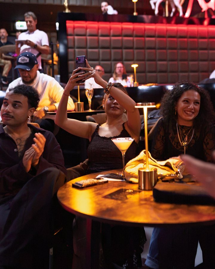 Guests applauding and filming the show from their table.