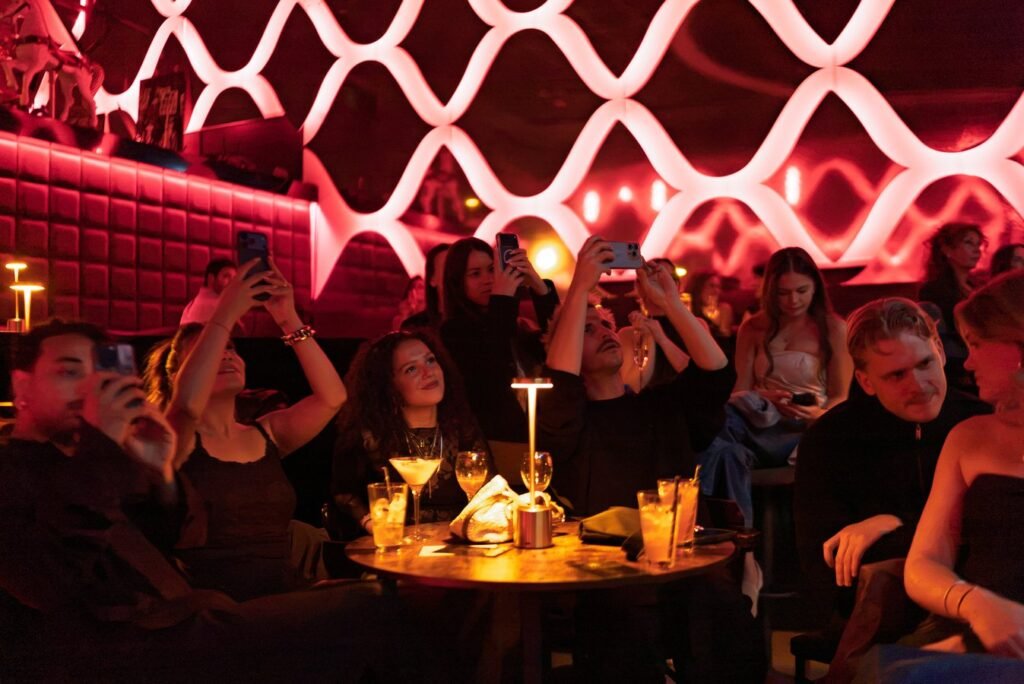Guests at a candlelit table filming the performance under the lattice lights.