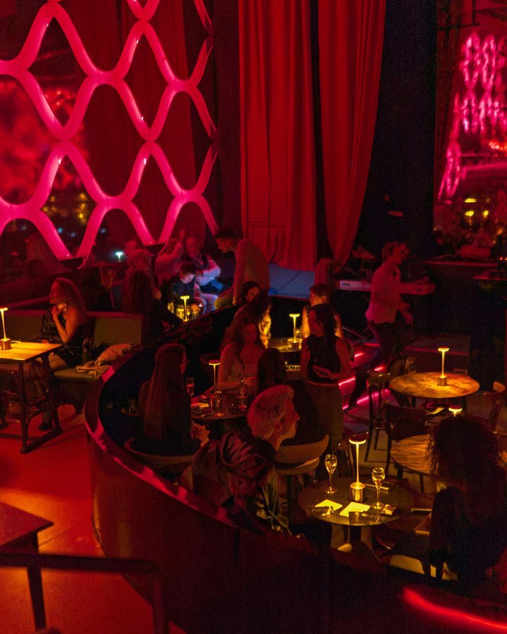 The red-lit Stable 54 room with guests at candlelit tables.