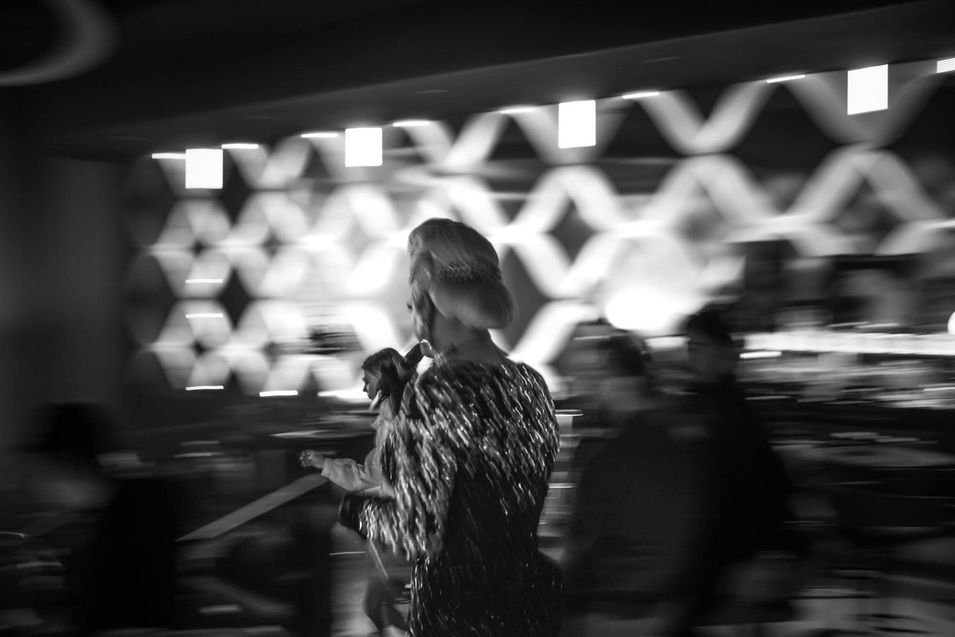 A singer in a fur coat performing to the room, in black and white.