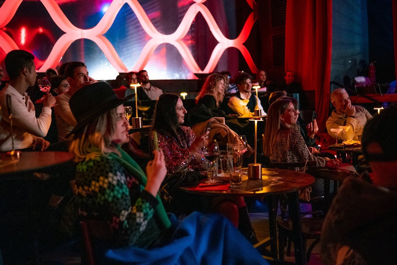 Guests at candlelit tables watching the show beneath the red lattice wall.