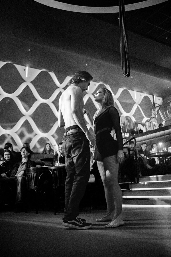 Two dancers face to face on the floor in front of the guests, in black and white.