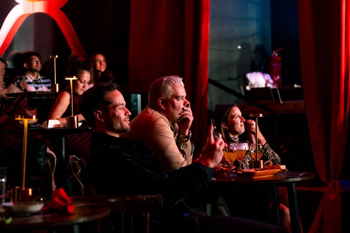 Guests at their tables watching the show between red curtains.