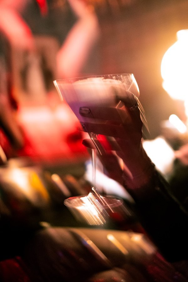 A guest holding a cocktail glass in the warm glow of the bar.