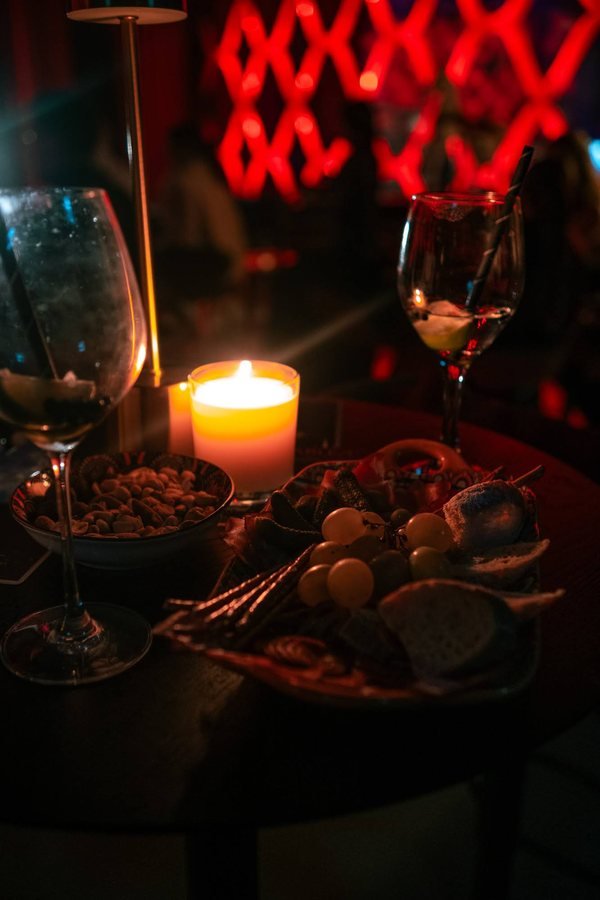A candlelit table with drinks, nuts and a fruit platter.