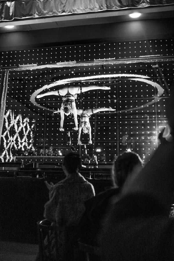 Guests watching two acrobats on the stage, in black and white.