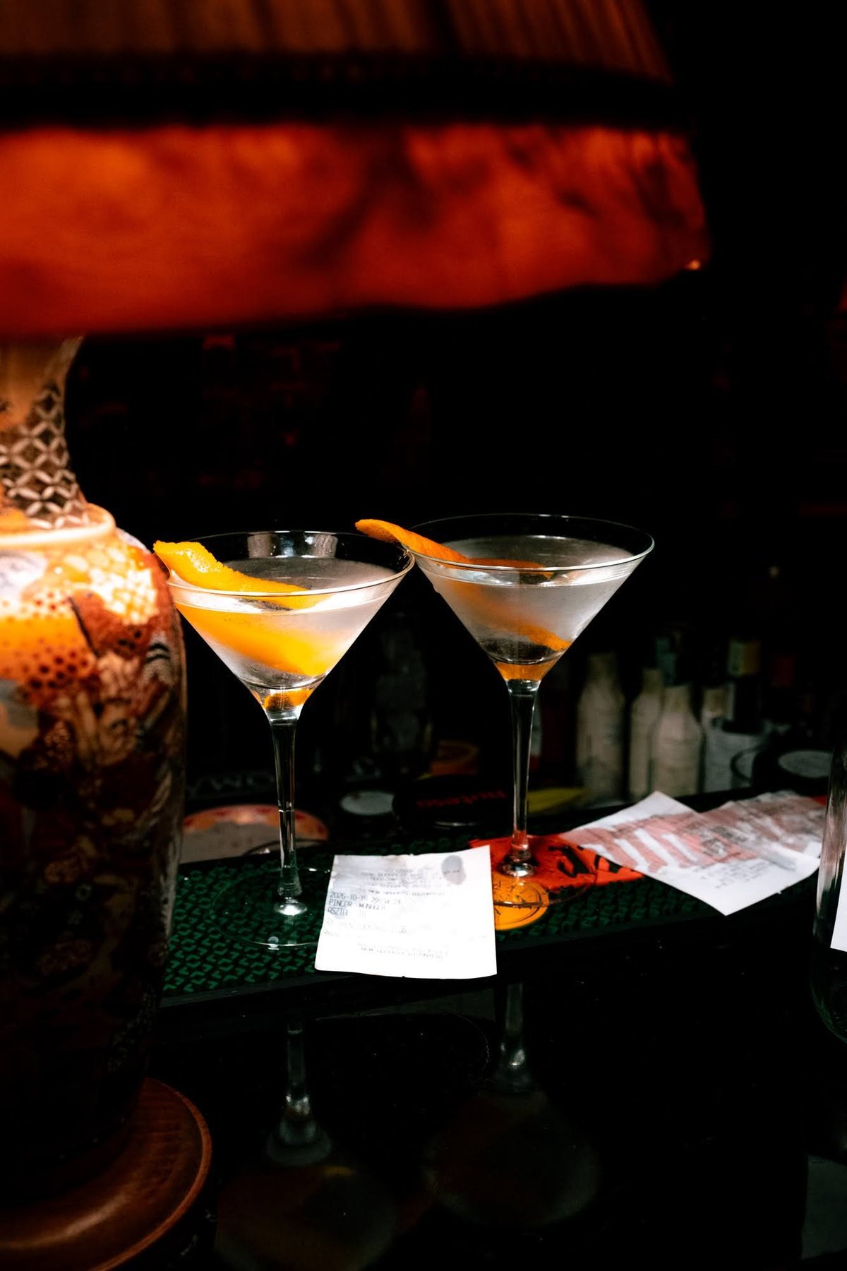 Two martinis with orange twists beside a lamp at the Stable 54 bar.